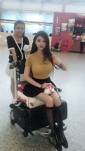 Chinese cutie sitting on a luggage cart
