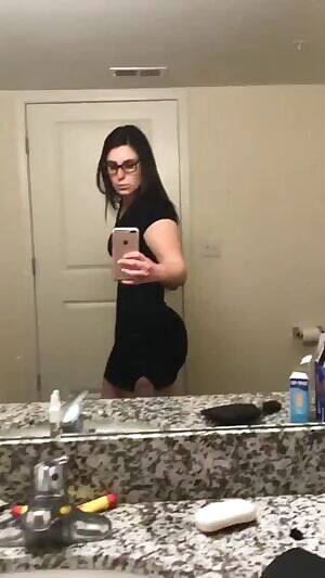 Checking out her figure in the mirror.